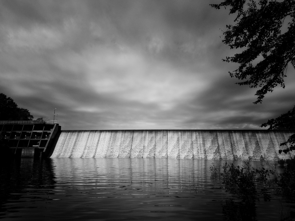 Water flowing over the Lake Bowen Dam in Inman, South Carolina, under an overcast sky.