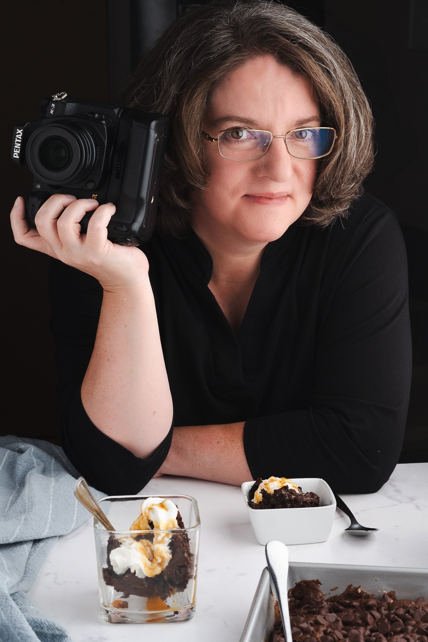 Heather Kitchen, photographer, portrait in natural light holding camera