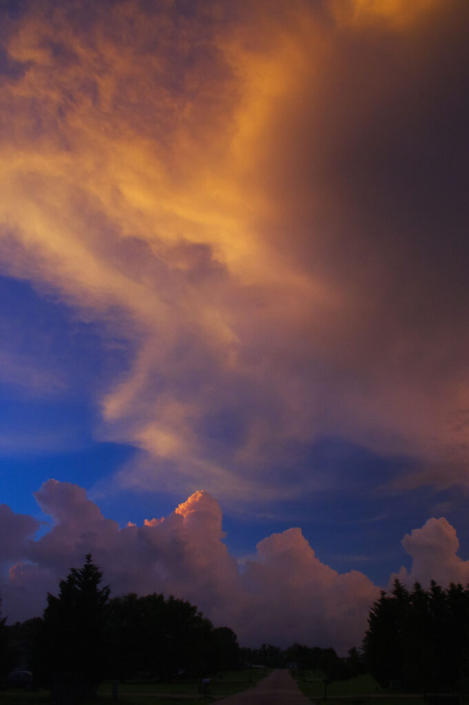 Vertical photograph of storm clouds glowing orange and purple over the South Carolina Upstate at sunset.