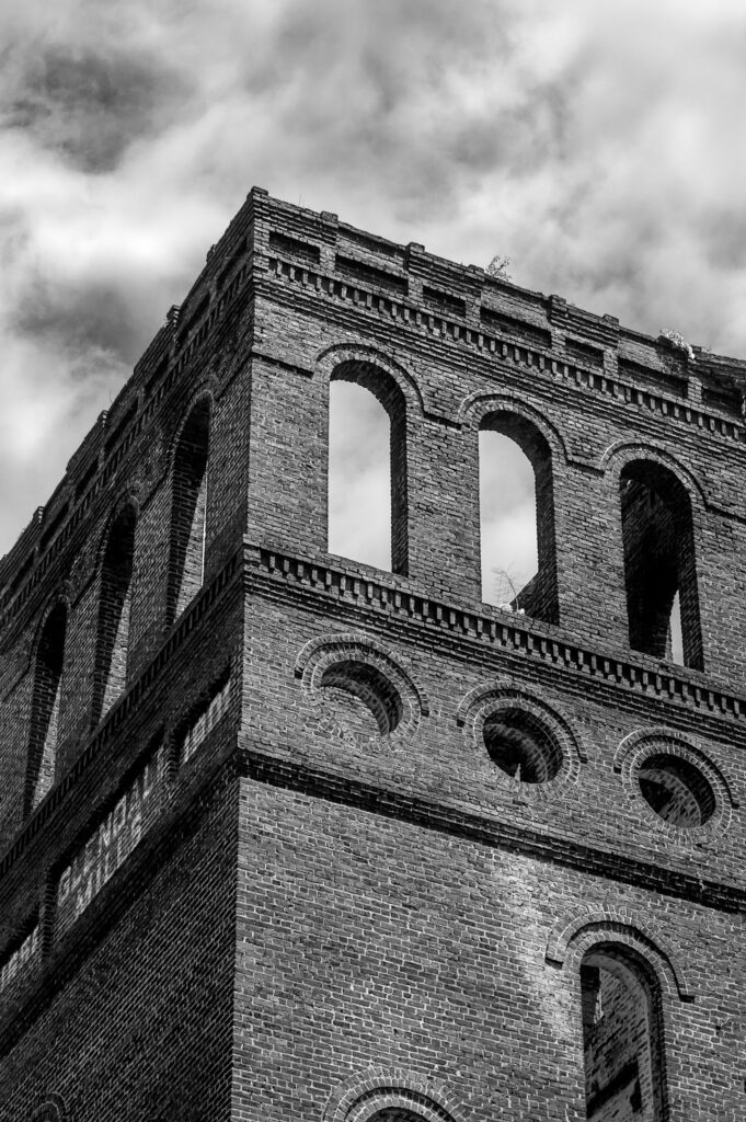 Brick tower structure at the Glendale Mill ruins in Glendale, South Carolina, beneath a bright cloudy sky.